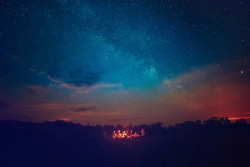 Poster Camping fire under the amazing blue starry sky with a lot of shining stars and clouds. Travel recreational outdoor activity concept. © Roxana