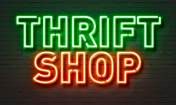 Thrift shop neon sign on brick wall background.