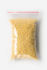 Plastic transparent zipper bag with full raw millet groats isolated on white, Vacuum package mockup with red clip. Concept.