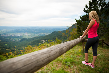 woman rests at fence after workout in nature