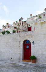 Entrance of a nice house with red outdoor. Facade of a building with door. Maltese architecture.