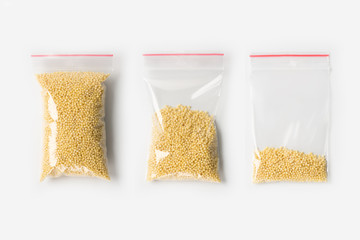 Set of three EMPTY, HALF AND FULL Plastic transparent zipper bag with raw millet groats isolated on white. Vacuum package mockup with red clip. Concept. © pavelvinnik