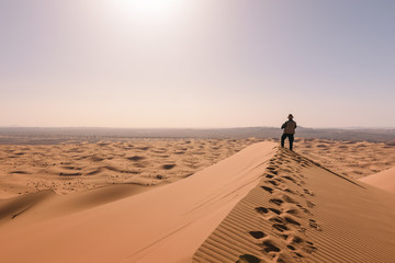 Fototapeta na wymiar Man overlooks the dunes of Erg Chebbi, Merzouga, Morocco