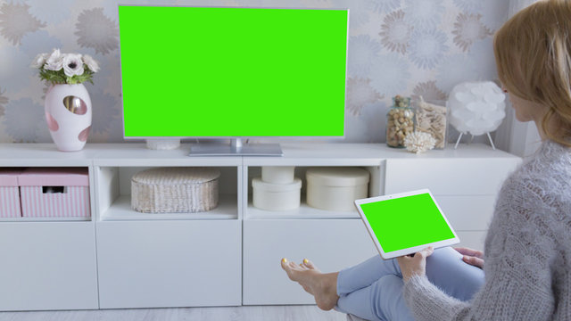 Woman at home relaxing reading on the tablet computer with pre-keyed green screen