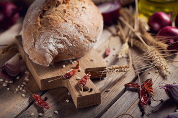 Fresh multigrain crusty bread and wheat ears on a rustic wooden table.