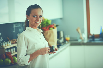 Happy woman drinking tea in the kitchen at home