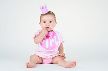 Girl with a crown, sitting in a bib on a white background.