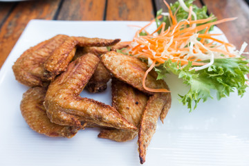 Chichen wing fried with salad in white dish on wooden table with copyspace ,flat lay ,selective focus