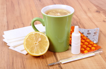 Pills and nose drops for colds, handkerchiefs and hot tea with lemon