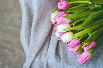 Bouquet of tulips with pink ribbon on gray blanket