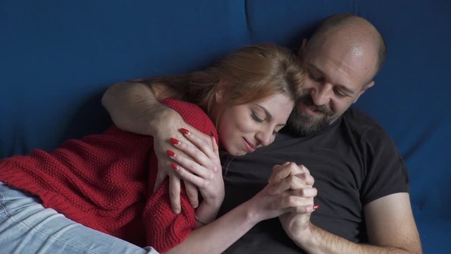 tender couple on blue sofa is cuddling gently