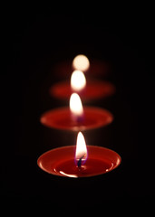 Red Burning candle isolated on black background.
