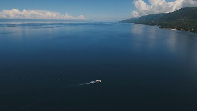 Aerial view of motor boat in sea. Aerial image of motorboat floating in a turquoise blue sea water. Sea landscape with wake of small fast motorboat. Tropical landscape. Philippines, Cebu. 4K video