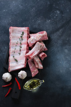 Top view of raw pork ribs on a dark metal background, copy space