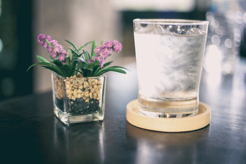 glass of water and fake flower on wood table