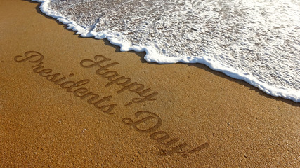 Happy Presidents Day Writing in Beach with Sand and Sea