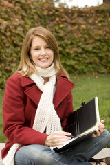 Woman sitting outside writing in a notebook.