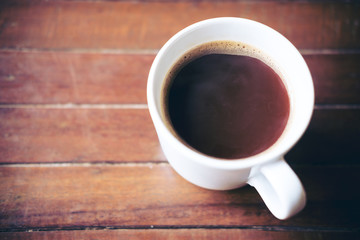 Closeup image of hot coffee cup on vintage wooden table in cafe