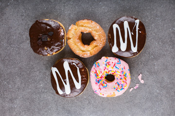 Five frosted donuts/doughnuts on a gray background