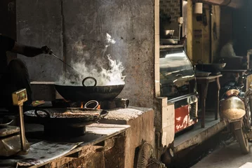 Foto auf Acrylglas Unrecognizable man cooking in fatiscent big pan or wok in a small street food stall. White smoke coming out from the pan, hand and arm only visible. Street food in India. © fabio lamanna