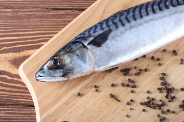 Свежая скумбрия для готовки на разделочной доске,фон деревянный.
