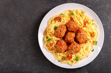 plate of pasta with meatballs on dark table