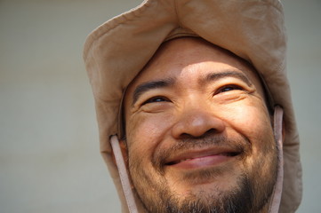 smiling face of beard asian man eith explored hat