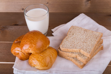 Three loaf bread  whole wheat breads and aglass of milk on linen