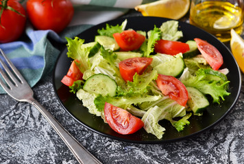 Vegetable salad with cucumber, tomatoes and olive oil on a concrete background