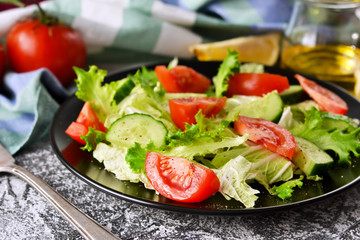 Vegetable salad with cucumber, tomatoes and olive oil on a concrete background