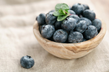 fresh blueberries in bowl on wood table with sack cloth