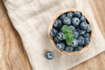 fresh blueberries in bowl on wood table with sack cloth