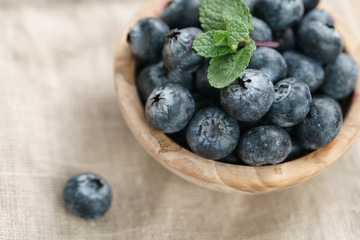 fresh blueberries in bowl on wood table with sack cloth
