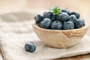 fresh blueberries in bowl on wood table with sack cloth