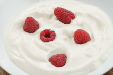 organic yogurt with fresh raspberries closeup, food background