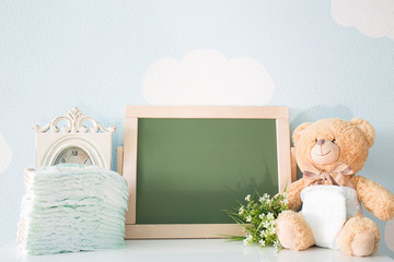 Diapers and blank chalkboard. Teddy bear dressed in diaper. top view. frame with a copy space