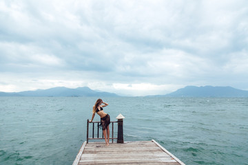 beautiful young brunette woman in black bikini posing on the beach. Sexy model portrait with perfect body. Concept of summer holidays