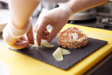 Chef is decorating crab salad with cucumber slices