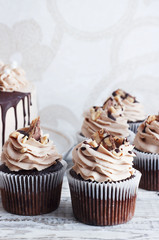 Chocolate cupcake with mousse cream icing on grunge white wooden background copy space