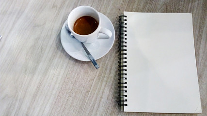 A Coffee cup and notebooks blank page on wooden table with copy space backgrounds