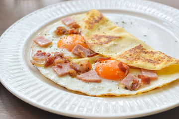Sunny side up egg crepe on white plate
