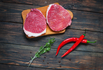 Fresh raw beef steak and chilli pepper on wood