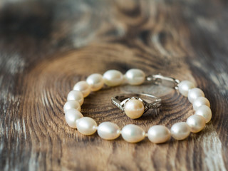 Fototapeta na wymiar Beautiful pearl braclet and ring on wooden background. Close up