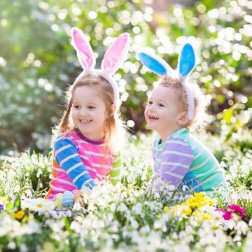 Kids on Easter egg hunt in blooming spring garden