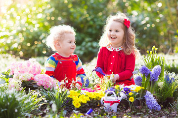 Kids plant and water flowers in spring garden