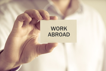 Businessman holding WORK ABROAD message card