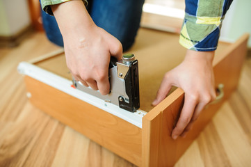 Worker repairing furniture with industrial/construction stapler
