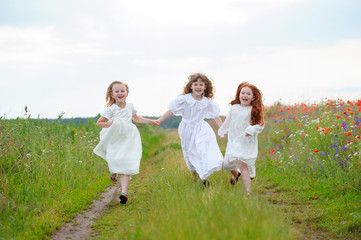 Naklejka na ściany i meble Three girls run approaching. Children playing at fresh 