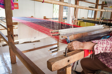 The old woman was weaving by hand weaving fabric, which has a unique look and feel of the people of Thailand.