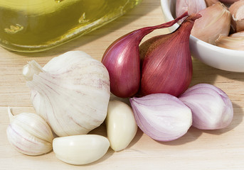 garlic, garlic cloves, onion and cooking oil on wooden background.